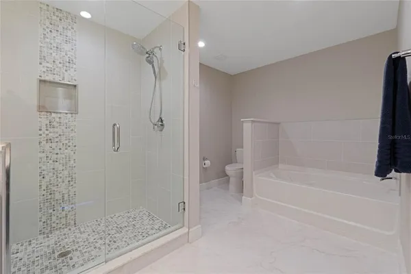 a bathroom with a tub shower and toilet
