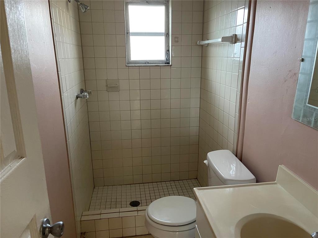 5924 Pine Street New Port Richey, FL 34652 - Photo 11 of 20 a white toilet sitting next to a bathroom sink and a shower