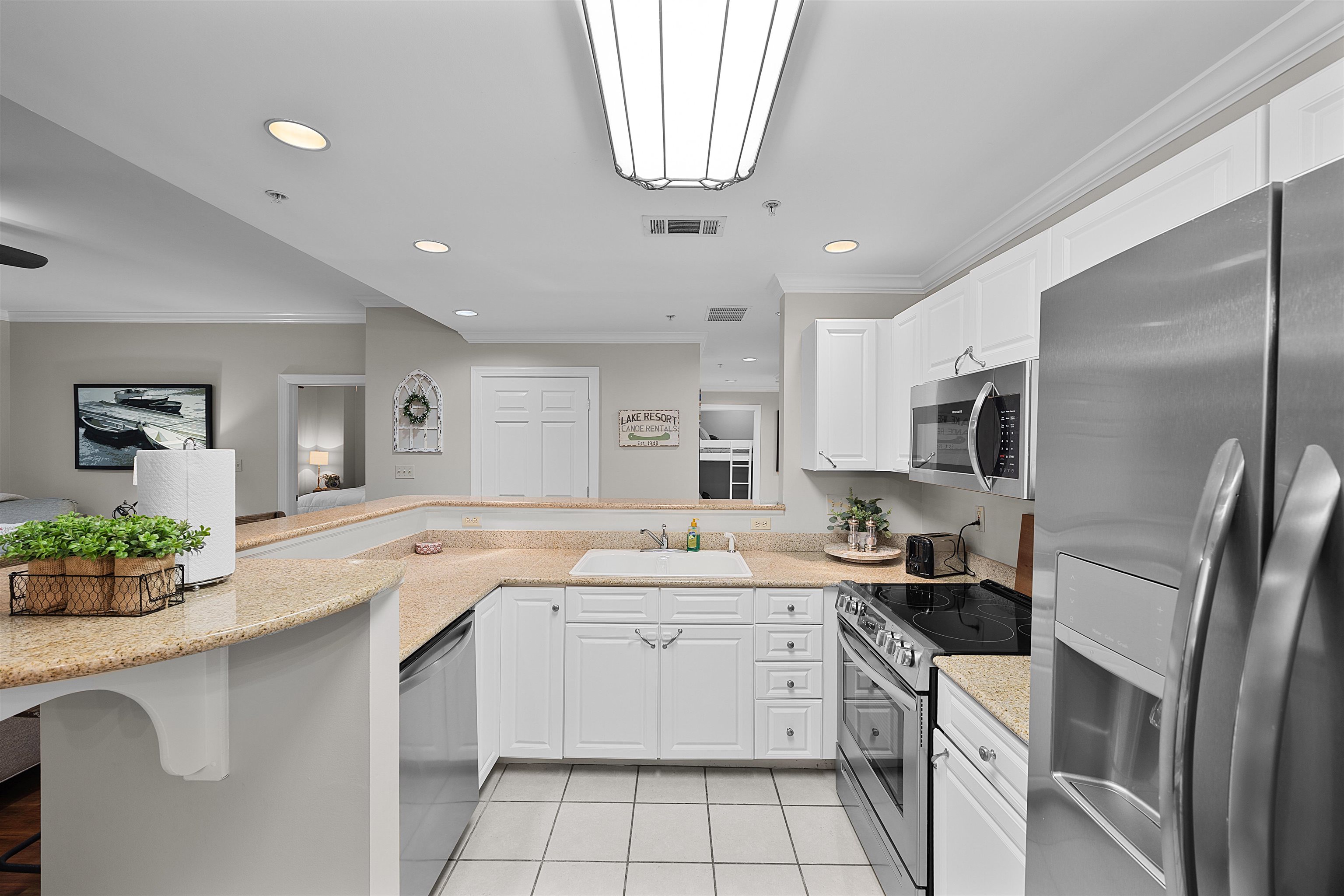 25 Cr 380 Road, Unit P 204 Iuka, MS 38852 - Photo 8 of 19 Kitchen with appliances with stainless steel finishes, a peninsula, crown molding, light tile patterned floors, and white cabinetry