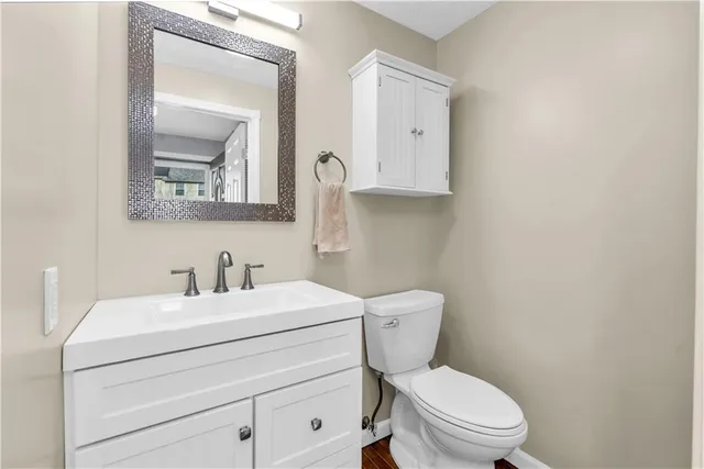 a bathroom with a toilet sink vanity and mirror