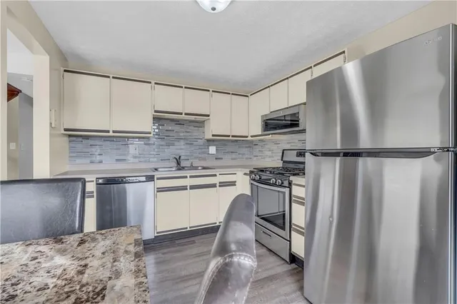 a kitchen with granite countertop a refrigerator stove and sink