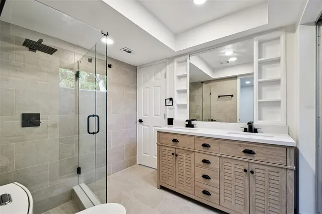a bathroom with a double vanity sink toilet mirror and shower