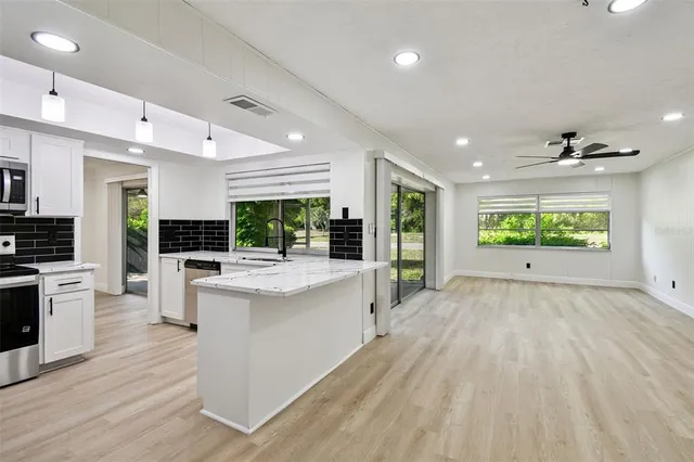 a large kitchen with stainless steel appliances granite countertop a large center island attached withe living room