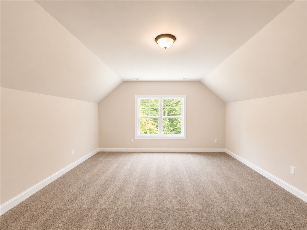 328 Point Road Westminster, SC 29693 - Photo 16 of 24 A spacious room with sloped ceilings and a window overlooking a verdant outdoor landscape.