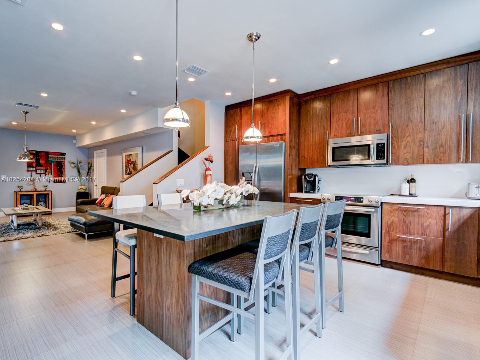 2993 Ruth Street, Unit 2993 Coconut Grove, FL 33133 - Photo 13 of 29 a kitchen with stainless steel appliances kitchen island granite countertop a stove a sink a dining table and chairs with wooden floor