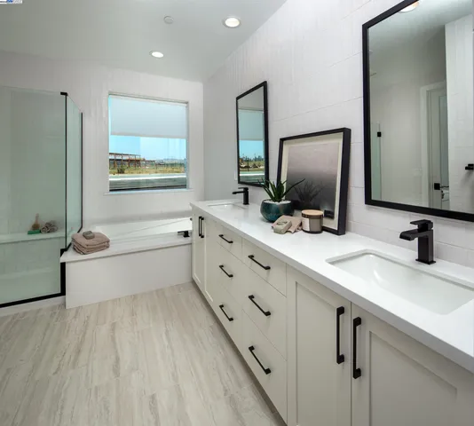 a bathroom with a double vanity sink a mirror and bathtub