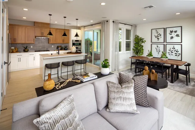 a living room with furniture kitchen view and a large window