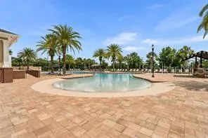 a view of swimming pool with a yard and palm trees