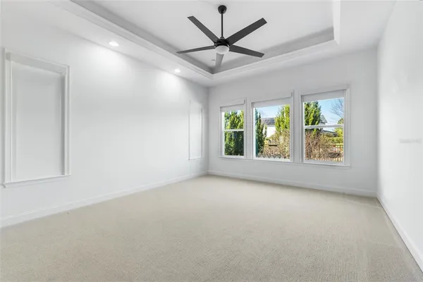 an empty room with windows and ceiling fan