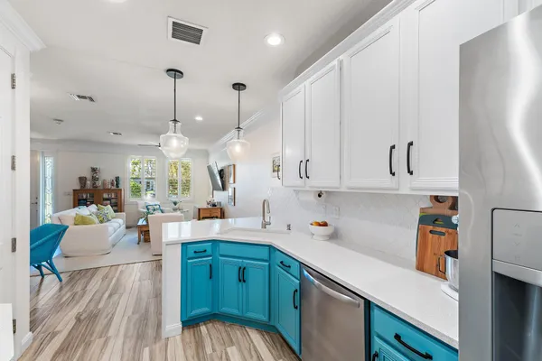 a kitchen with stainless steel appliances kitchen island granite countertop a sink dishwasher and a white cabinets with wooden floor