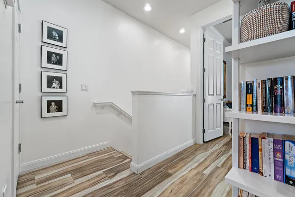a view of hallway with wooden floor and cabinets