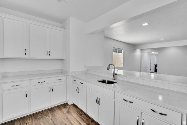 3269 West 650 North Layton, UT 84041 - Photo 22 of 35 Contemporary kitchen featuring white shaker cabinetry, light-toned countertops, a stainless steel sink with a high-arch faucet, recessed lighting, and wood-finish flooring