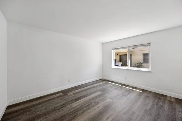 a kitchen with granite countertop a refrigerator a sink and white cabinets