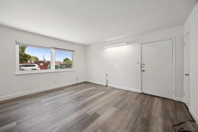 a view of an empty room with wooden floor and a window