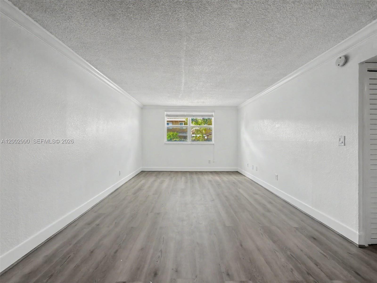 606 West 81st Street, Unit 120 Hialeah, FL 33014 - Photo 11 of 14 an empty room with wooden floor and windows
