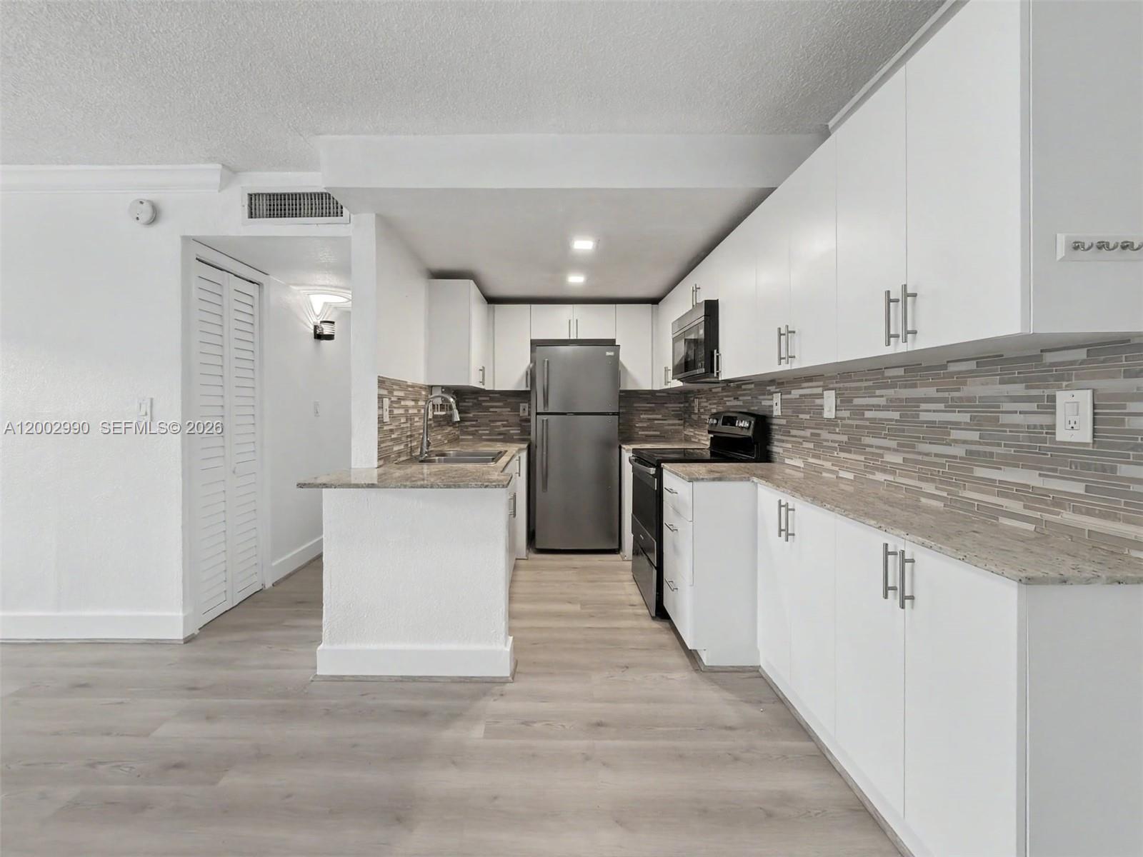 606 West 81st Street, Unit 120 Hialeah, FL 33014 - Photo 2 of 14 a kitchen with refrigerator and cabinets