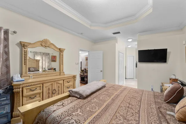 a bedroom with a bed a mirror and a flat tv screen on dresser