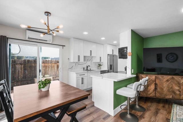 a open kitchen with stainless steel appliances granite countertop a stove a refrigerator a dining table and chairs with wooden floor