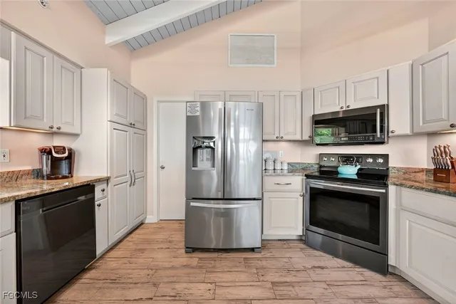 a kitchen with granite countertop a refrigerator stove and microwave
