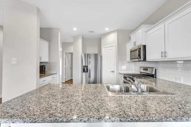 a kitchen with stainless steel appliances granite countertop a refrigerator stove and sink