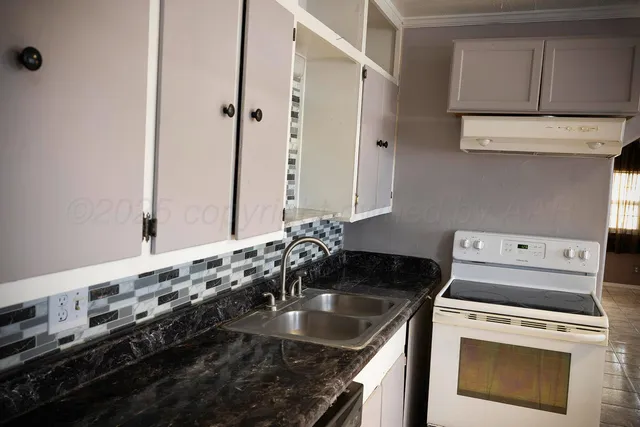 a kitchen with granite countertop a sink stove and cabinets