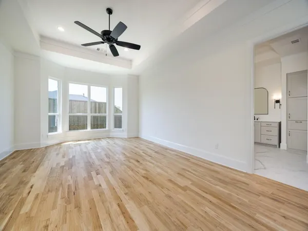a view of empty room with wooden floor and ceiling fan