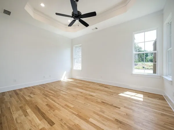 an empty room with wooden floor fan and windows