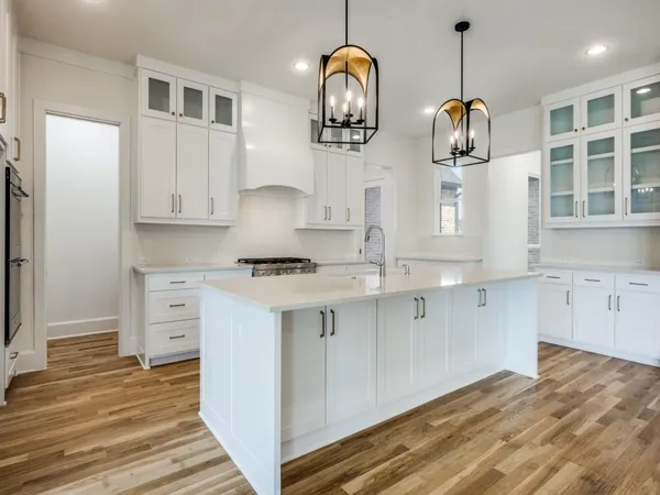 a kitchen with stainless steel appliances granite countertop a stove and white cabinets with wooden floor