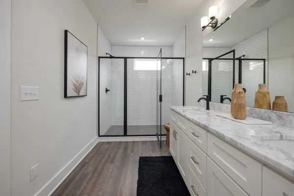 a spacious bathroom with a double vanity sink a mirror and shower