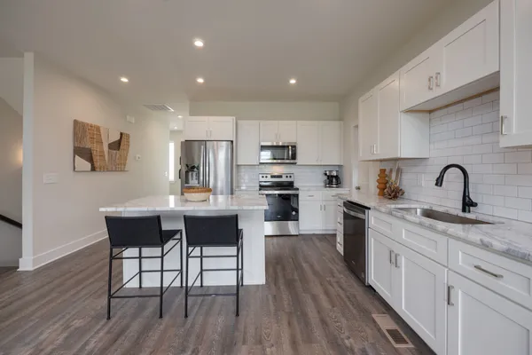 a kitchen with stainless steel appliances granite countertop a table chairs microwave and sink