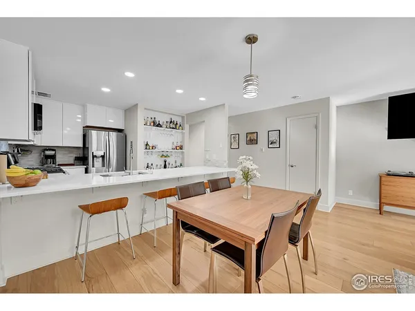a kitchen with stainless steel appliances granite countertop a dining table chairs sink refrigerator and granite counter top