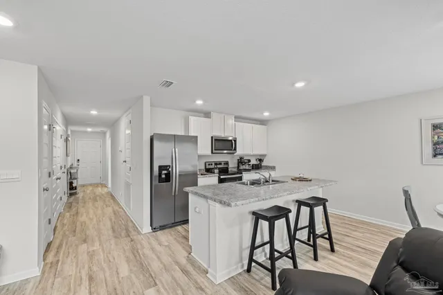 a kitchen with stainless steel appliances granite countertop a sink a stove a refrigerator a counter top space and cabinets