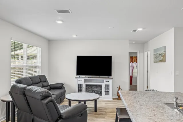 a kitchen with stainless steel appliances granite countertop a stove top oven a sink a dining table and chairs with wooden floor