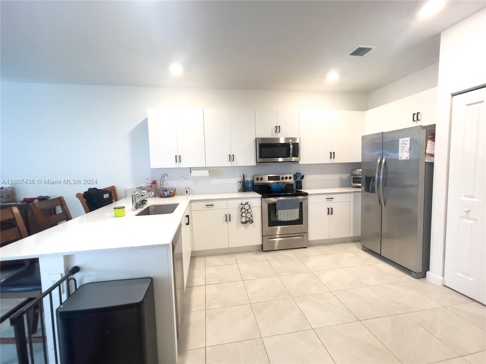 13414 Southwest 286th Street, Unit 13414 Homestead, FL 33033 - Photo 5 of 34 a kitchen with stainless steel appliances a stove a sink a microwave a refrigerator and cabinets