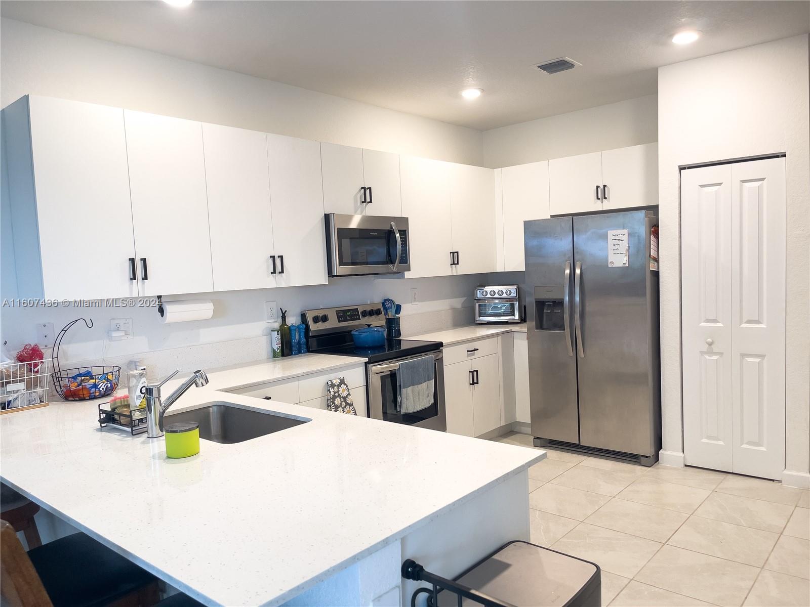 13414 Southwest 286th Street, Unit 13414 Homestead, FL 33033 - Photo 7 of 34 a kitchen with stainless steel appliances a refrigerator sink and white cabinets
