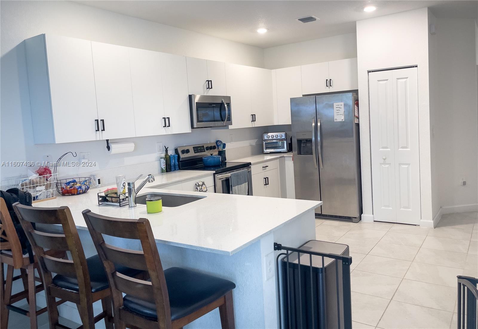13414 Southwest 286th Street, Unit 13414 Homestead, FL 33033 - Photo 8 of 34 a kitchen with a dining table cabinets and refrigerator