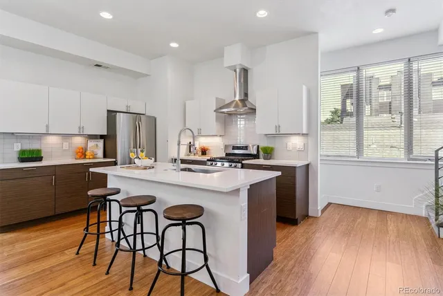 a kitchen with stainless steel appliances a dining table chairs stove refrigerator and cabinets