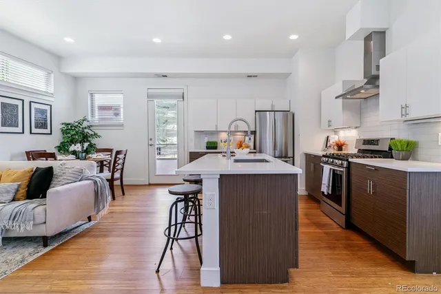 a kitchen with stainless steel appliances granite countertop a table chairs refrigerator and sink