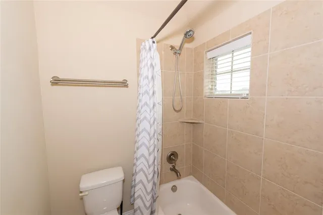 a bathroom with a shower a toilet and a window