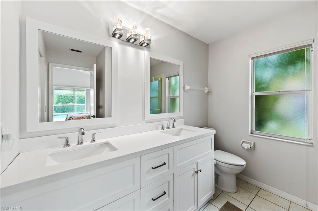 511 Ibis Way Naples, FL 34110 - Photo 23 of 46 a bathroom with a double vanity sink toilet and mirror