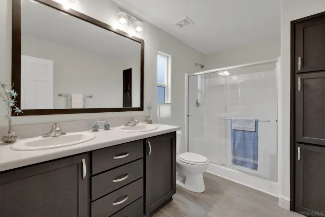 a bathroom with a double vanity sink toilet mirror and shower