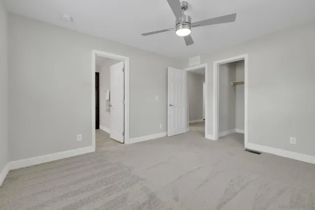 an empty room with closet and a ceiling fan