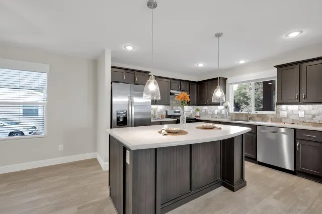 a kitchen with stainless steel appliances granite countertop a sink a stove and a refrigerator