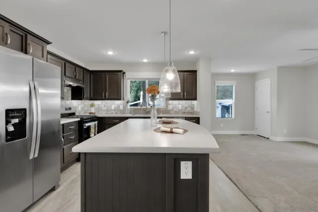 a kitchen with kitchen island stainless steel appliances a sink stove and refrigerator