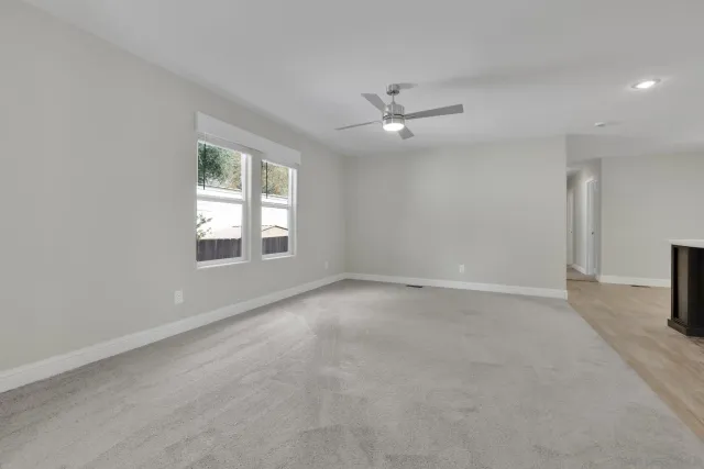 an empty room with windows and ceiling fan