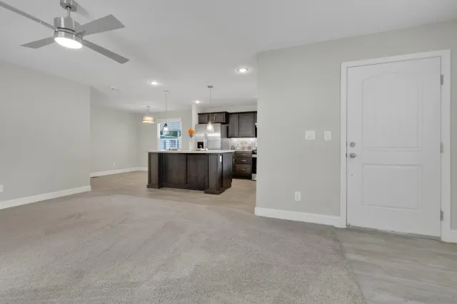 an empty room with kitchen and ceiling fan