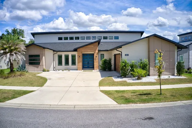 a view of a white house with a small yard and plants