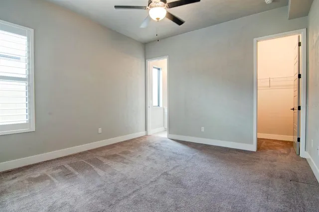 an empty room with chandelier fan and windows