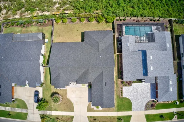 an aerial view of residential houses with outdoor space and parking