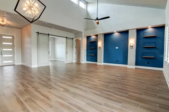 a view of an empty room with wooden floor and a ceiling fan